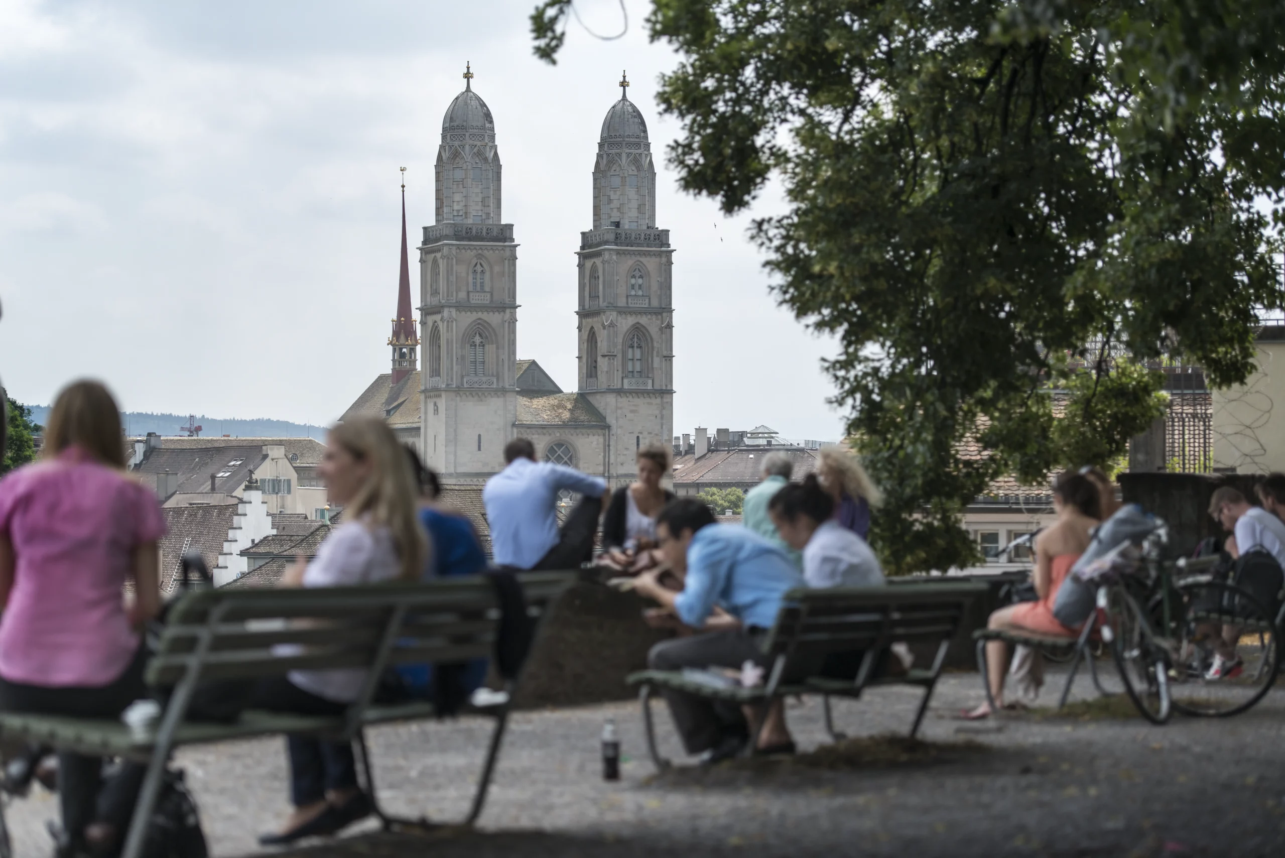 People relaxing at Lindenhof in Zurich with the Grossmünster towers in the background
