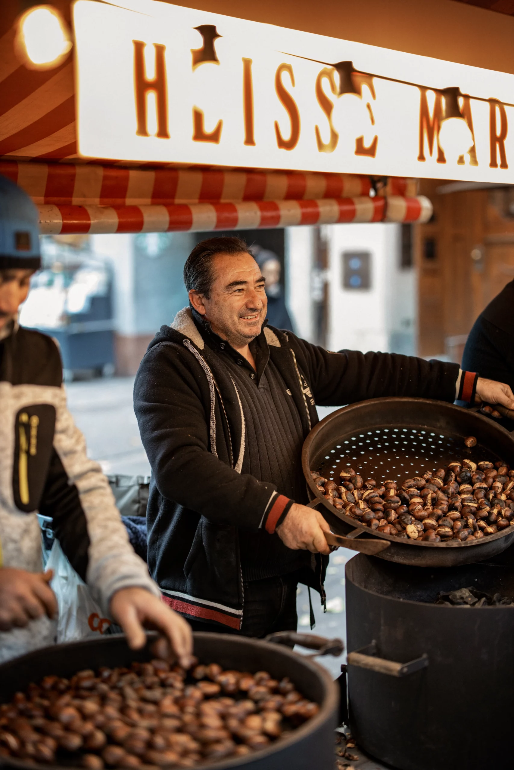Person selling roasted chestnuts at a Zurich street market
