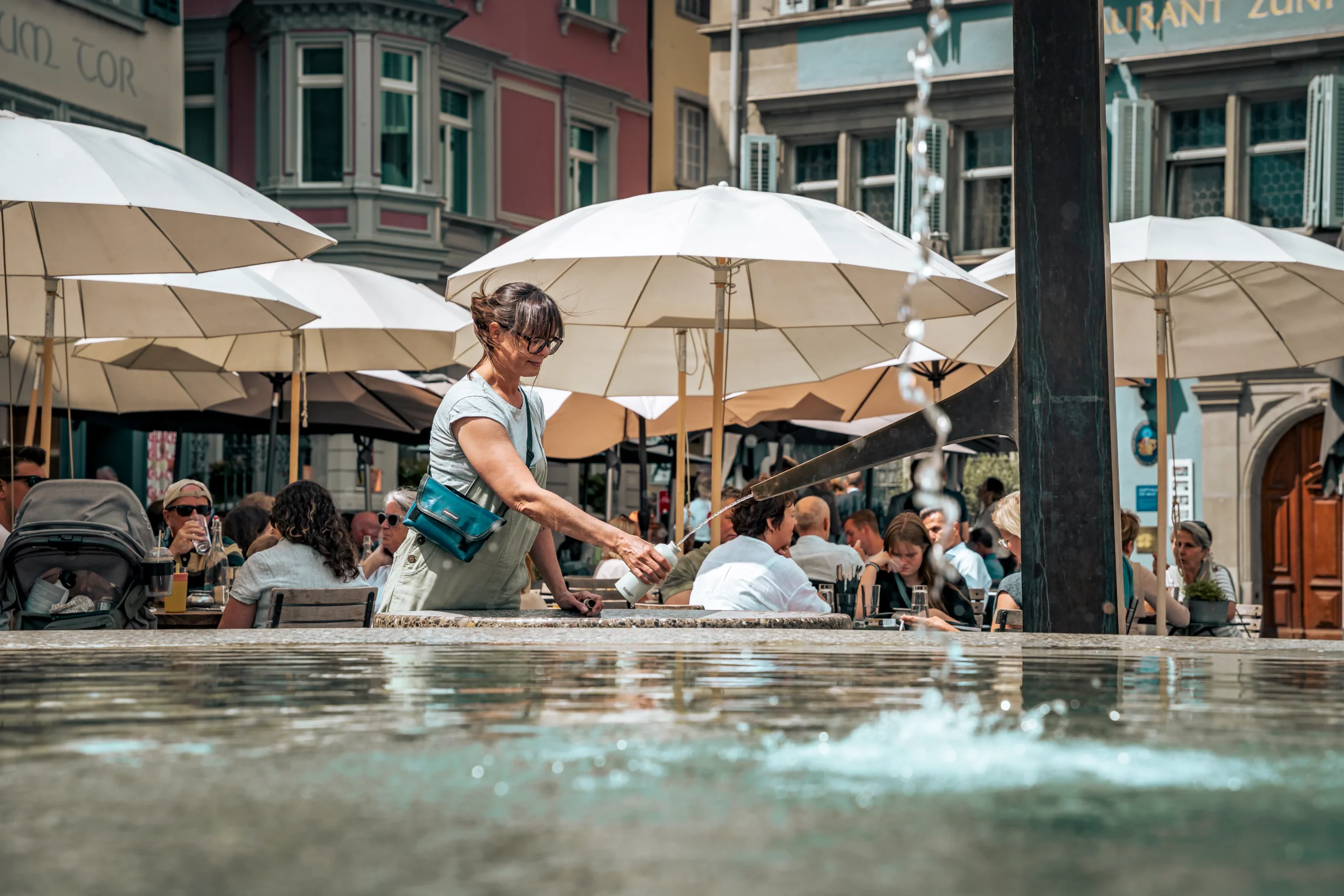 Münsterhof fountain in Zurich Old Town with people relaxing around the water